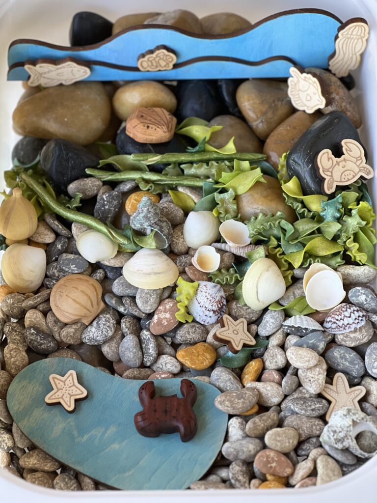 rock pool sensory bin with painted beans, pasta and wood toys